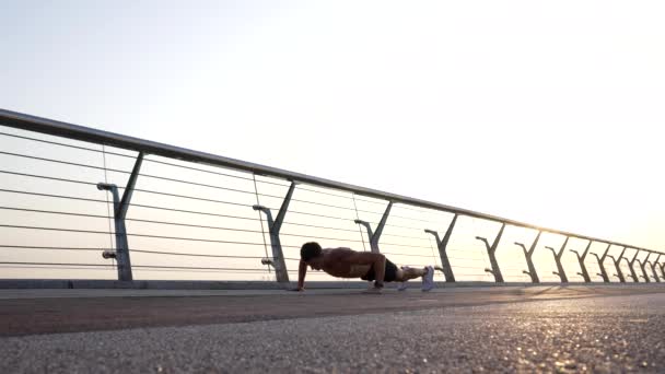 Atlético chico con torso muscular hacer flexiones al aire libre, entrenamiento de la mañana — Vídeos de Stock
