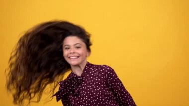 Mutlu çocuk uzun, sağlıklı kıvırcık saçlarını sallıyor şampuanını sunuyor, güzellik