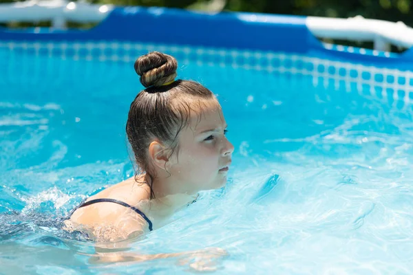 落ち着いて泳いでください。女の子の子供はプールで泳ぐ。夏休みだ。熱い太陽と澄んだ水 — ストック写真