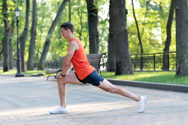 L'homme athlétique tient la position de la fente. Étirement de la jambe après l'entraînement. Stretching routine — Photo