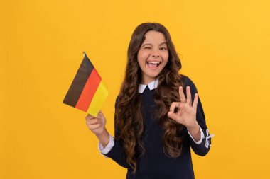 Mutlu göz kırpan çocuk, Almanya bayrağı sarısı arka planda tut. İyi niyet göstergesi, yurt dışında eğitim