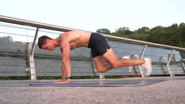 Atlético muscular homem no sportswear fazer montanha alpinista exercício na parte da manhã, executar prancha — Vídeo de Stock