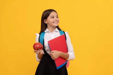 Mutlu çocuk gülümsüyor elinde kitaplar ve elma sarısı arka plan, okulda atıştırmalık