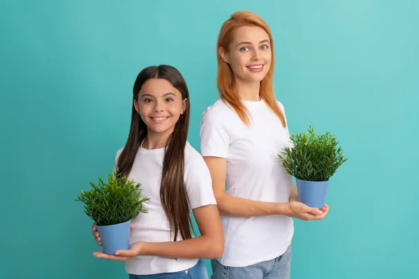 Rodzina adopcyjna adoptowanego dziecka córka i kobieta matka uśmiechają się trzymając rośliny doniczkowe, przybrane — Zdjęcie stockowe