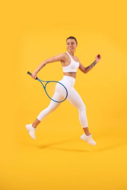 Spor oyunu ve hobi. Yaz etkinliği. Spor kıyafetli gülümseyen genç kız raketle koşar.