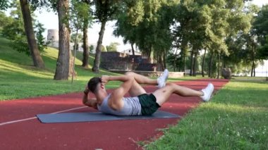 Sporcu adam kas kasları için bisiklet egzersizi yapıyor, dışarıda, antrenman yapıyor.