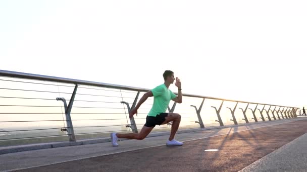 Deportivo chico entrenador calentamiento con espalda embestida ejercicio al aire libre, fitness — Vídeos de Stock