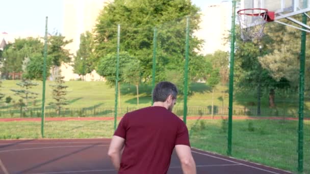 Hombre jugando baloncesto lanzando pelota en la cesta en el patio de recreo, deporte — Vídeos de Stock