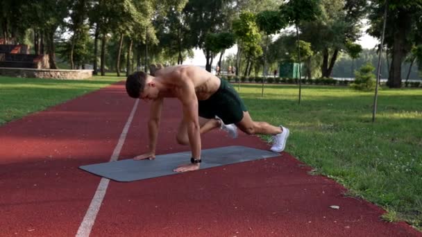 Hombre haciendo rock mountain ejercicio en la alfombra de fitness en el parque, desafío — Vídeos de Stock