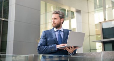 Resmi takım elbiseli ciddi sakallı iş adamı internette çalışıyor, başarılı.