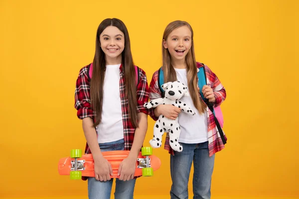 Meninas adolescentes felizes carregam brinquedo mochila e penny board. de volta à escola. dia do conhecimento. — Fotografia de Stock