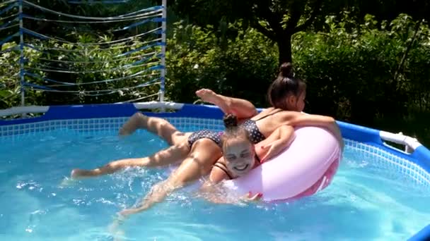 Chicas felices se divierten flotando juntos en el anillo de natación en la piscina al aire libre, verano — Vídeos de Stock