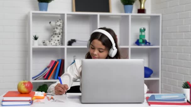 Estudiante alegre chica en los auriculares estudio en la escuela lección en línea con el ordenador portátil, dispositivo moderno — Vídeos de Stock