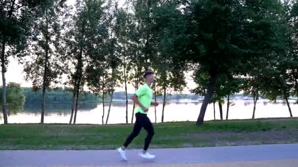 Homme athlétique en vêtements de sport courant à la rivière en plein air, exercice du matin — Video