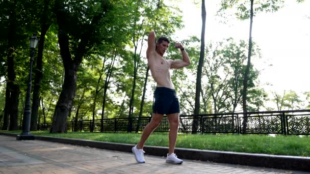 Homem muscular mostrando músculos laterais fisiculturista ao ar livre, forma do corpo — Vídeo de Stock