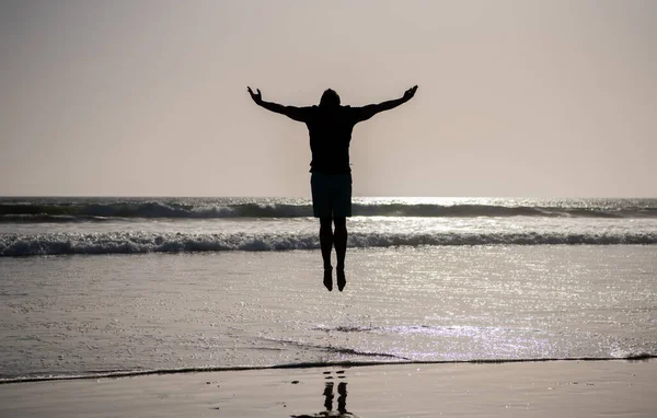 Sylwetka sportowca skok z podniesionymi rękami na letniej plaży, inspiracja — Zdjęcie stockowe