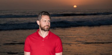 Gündoğumu plajındaki beyaz adam. Gömlekli sakallı adam. Yaz modası.