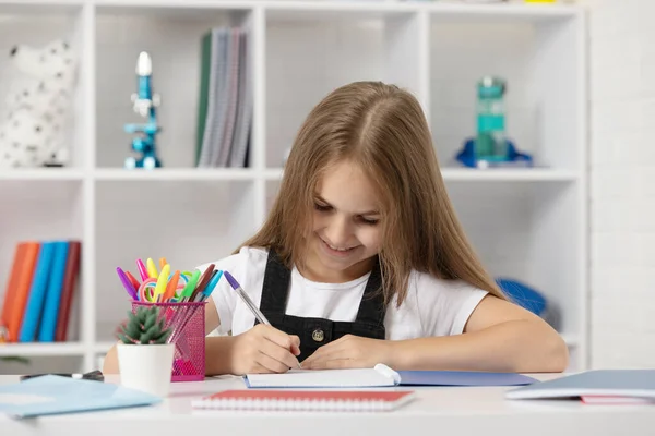 Heureux enfant écriture dans copybook à l'école leçon en uniforme de vêtements de classe, retour à l'école — Photo