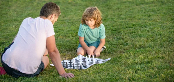 Táta a děcko hrají logickou hru. kopírovat prostor. otec a syn hrají šachy v parku. Den otců. — Stock fotografie