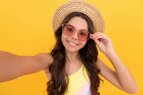 Happy child in summer straw hat and glasses making selfie on yellow background, childhood — Stock Photo, Image