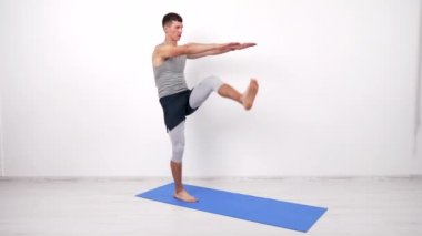 Konsantre sporcu karın kasları egzersizi yapıyor, bacak yukarıda spor minderinde, hareket halinde.