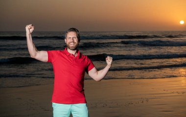 Başarıyı kutlamak. kopyalama alanı. Gün batımında deniz üzerinde sakallı mutlu bir adam. başarılı adam