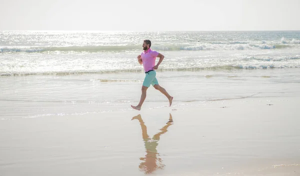 Atlético hombre corredor corriendo descalzo en verano playa, deporte —  Fotos de Stock