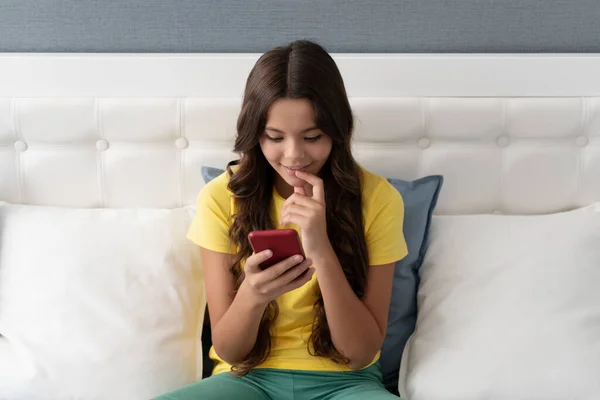 Smartphone-generationen. Glad barn använda smartphone sitter på sängen. Chatta på smarttelefon — Stockfoto