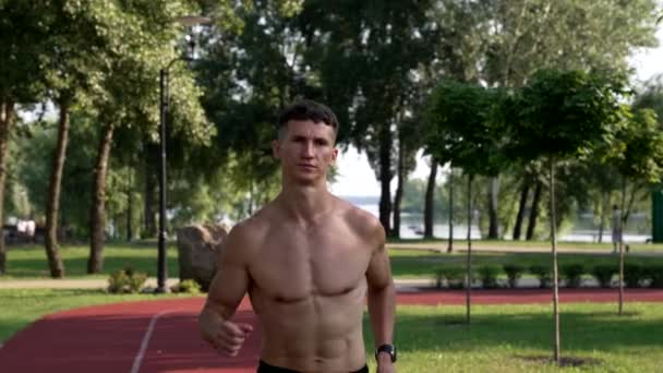 Motivación del joven atleta muscular corre en pista de atletismo en parque, competición — Vídeos de Stock