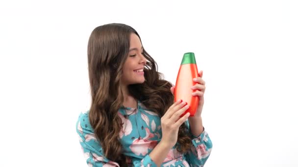 Happy child girl with curly hair presenting cosmetic product for teen showing thumb up, haircare. — Stock Video