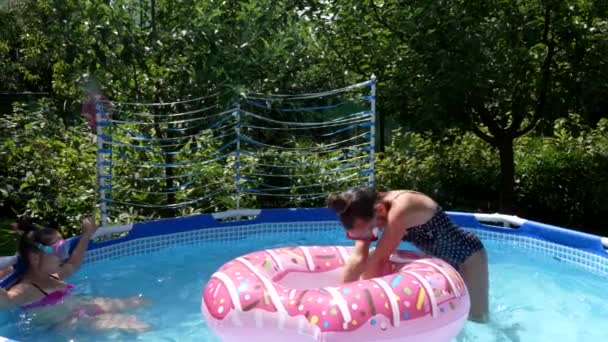 Kinder in Schutzbrillen chillen und tauchen im Sommer gerne durch Donut-Schwimmer im Schwimmbad, tauchen — Stockvideo