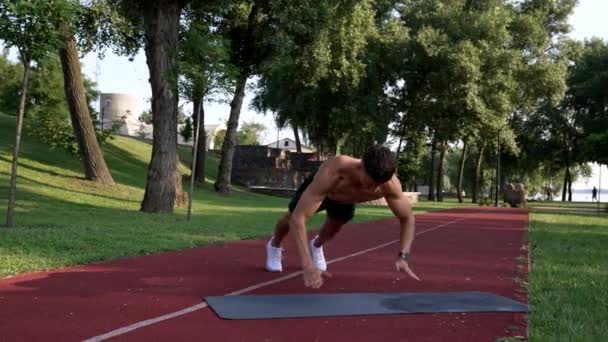 Pria berotot melakukan pushups dengan bertepuk tangan di atas tikar kebugaran dengan tubuh telanjang, triceps — Stok Video