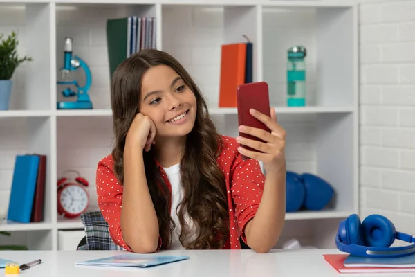 Glad barn lockigt hår gör selfie på telefonen i klassrummet, vloggning — Stockfoto