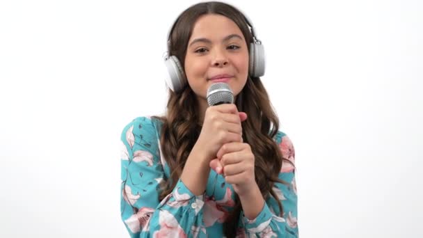 Cheerful teen girl in headphones with microphone talk to camera interviewing or singing, technology — Stock Video