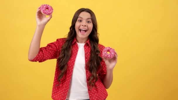 Felice ragazza adolescente con dolce ciambella divertirsi su sfondo giallo, panetteria — Video Stock