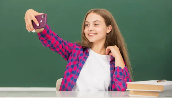 Enfant heureux faisant selfie sur smartphone en classe au tableau noir, portrait — Photo