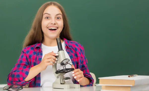 Lisede mikroskop kullanan mutlu bir genç kız. — Stok fotoğraf