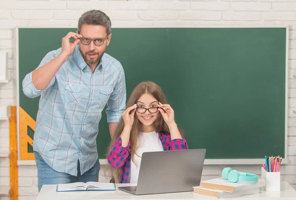 Verbaasd kind en vader zitten in de klas met computer op schoolbord, e-learning — Stockfoto