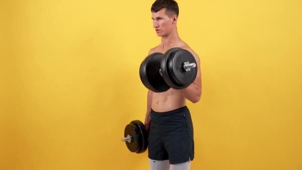 Atlético muscular desportista levantamento de fitness barbell no fundo amarelo, motivação — Vídeo de Stock