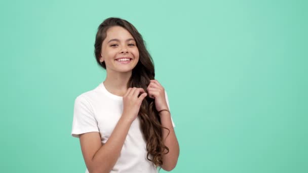 Nastolatek dziewczyna dotknąć jej gładkie długie kręcone włosy z szczęśliwy twarz cios pocałunek, fryzjer koncepcja — Wideo stockowe