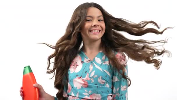 Veselý dospívající dívka soustružení prezentaci pomocí canditioner láhev izolované na bílém, reklama. — Stock video