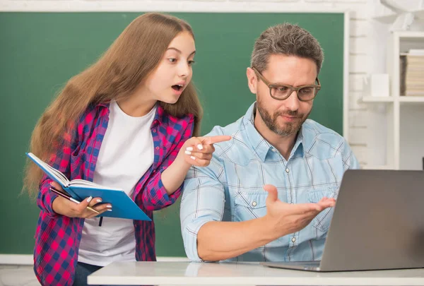 Užaslý žák a lektor s laptopem. otec a dospívající dívka studují. soukromý učitel a dítě — Stock fotografie