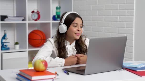 Estudiante sonriente chica en los auriculares estudio en la escuela lección en línea con el ordenador portátil, comunicación — Vídeos de Stock