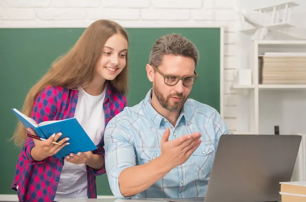 Terug naar school. onderwijs aan kinderen. Lachende leerling en mentor met laptop. vader en tiener meisje — Stockfoto