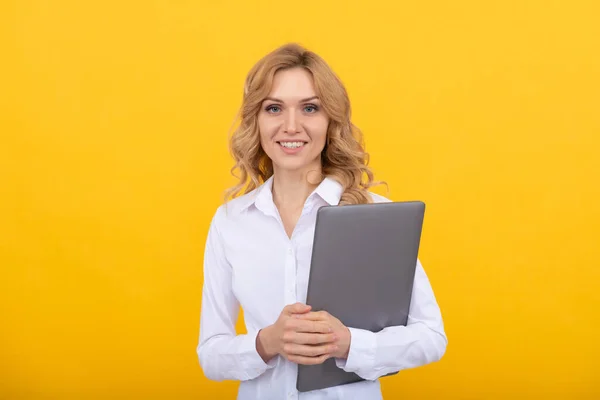 Beyaz gömlekli gülümseyen iş kadını dizüstü bilgisayarı sarı arka planda tutuyor. — Stok fotoğraf