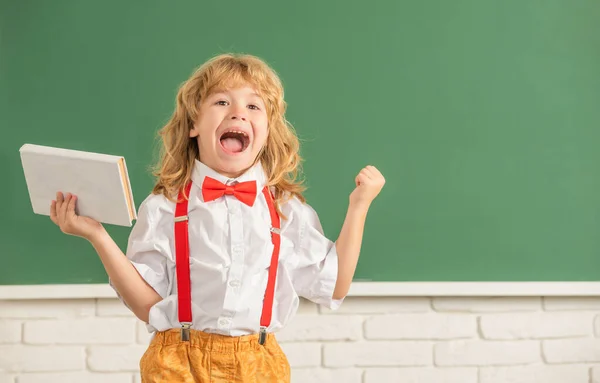 Niño feliz en el estudio de la corbata de lazo en el aula de la escuela con cuaderno que se divierte, espacio de copia, educación — Foto de Stock