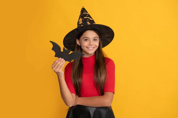 Niño sonriente con murciélago con sombrero de bruja sobre fondo amarillo, halloween — Foto de Stock