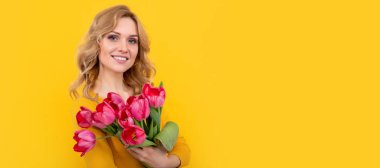 Sarı arka planda bahar lale çiçekleriyle gülümseyen genç bir kadın. İzole edilmiş yüz portresi, taklit alanı olan pankart
