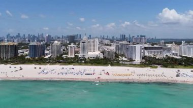 Miami 'de kumsalda güneşli yataklı, okyanus dalgalı bir plaj. Muhteşem manzaralı Miami Beach cenneti. Güney Sahili Miami cankurtaranı. Miami 'de huzurlu deniz kenarı inzivası