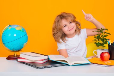 Okullu çocuk harika bir fikirle işaret parmağını kaldırıyor. Okula dönelim. Sarı stüdyo arka planında izole edilmiş şirin çocuk portresi. Okul ve eğitim çocukları konsepti